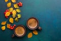 Two brown clay cups of black coffee, branches with small autumn leaves Spiraea Vanhouttei and red Rowan`s fruits on dark blue-