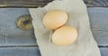 Two brown eggs on craft paper on a wooden surface Royalty Free Stock Photo