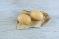 two brown eggs on craft paper on a wooden surface Royalty Free Stock Photo