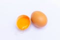 Two brown eggs With one egg broken in half, with a yolk inside the eggshell, laid on a white background Royalty Free Stock Photo