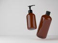 Two brown glass bottles for shower gel and liquid soap floating on studio background, 3D render of cosmetic product Royalty Free Stock Photo