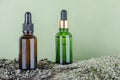Two brown, green glass bottles with serum, essential oil or other cosmetic product on tree bark covered with moss