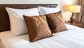 Two brown pillows with leaf pattern on a white striped bed with a leather headboard cushion Royalty Free Stock Photo