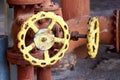 Two brown retro design industrial valves with yellow handwheels over concrete industrial background of chemical plant with