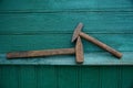 Two old hammers lie on a green wooden wall Royalty Free Stock Photo