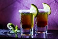 two brown shot cocktails garnished with lime and salt. on the bar