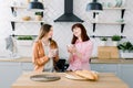 Two brunette girls friend drinking coffee or green tea talking. Couple of woman eating breakfast together on kitchen Royalty Free Stock Photo