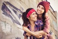 Two Brunette teenage girls friends in hipster outfit (jeans shorts, keds, plaid shirt, hat) with a skateboard at the park outdoors Royalty Free Stock Photo