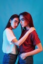 Two brunettes. Studio shot indoors with neon light. Photo of two beautiful twins