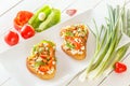 Two Bruschetta with red sweet pepper and goat cheese in a plate next to fresh vegetables Royalty Free Stock Photo