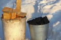 Two buckets filled with coal and wood are standing on the snow