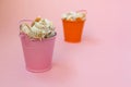 Two buckets filled with seashells on a pink background. Orange and pink bucket. There is a place for text Royalty Free Stock Photo