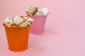 Two buckets filled with seashells on a pink background. Orange and pink bucket. There is a place for text. Royalty Free Stock Photo