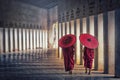 Two buddhist monk novice holding red umbrellas and walking in pa Royalty Free Stock Photo