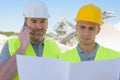 two builders on construction site looking at plans Royalty Free Stock Photo