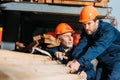two builders in helmets working with wooden planks outside Royalty Free Stock Photo