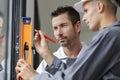 two builders holding spirit level against window