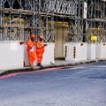 Two Builders In Orange Overalls And Hard Hats