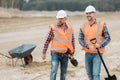 Builders in orange vests and helmets working on the road construction field