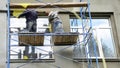 Two building contractors on scaffoldings are plastering, applying stucco finish, rendering, coating the facade wall of a house