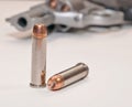 Two bullets with a stainless revolver in the background