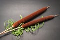 Two bulrushes and green bast lie on a black background.