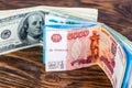 A two bunches of russian rubl and us dollar banknotes standing on brown wood surface close-up with selective focus