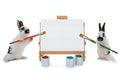 Two bunnies stand at easel with tassels isolated on a white background Royalty Free Stock Photo