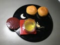 two buns and a cup of hot green tea on black round tray for serve afternoon tea time Royalty Free Stock Photo