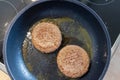 Two burger patties burger meat sizzling in hot pan with fat and oil as delicious selfmade hamburger bbq meatballs as unhealthy fas Royalty Free Stock Photo