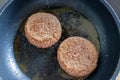 Two burger patties burger meat sizzling in hot pan with fat and oil as delicious selfmade hamburger bbq meatballs as unhealthy fas Royalty Free Stock Photo