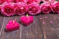 Two burning candles and beautiful pink roses on the wooden background Royalty Free Stock Photo