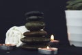 Two burning candles, white towel and some stones in black background used for relaxing concepts as yoga, massage concept of Royalty Free Stock Photo