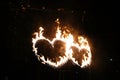 Two burning hearts at night, flame in the shape of sparkling love sign