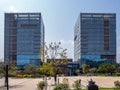 Two business buildings with glass exterior and plaza with trees on blue sky background Royalty Free Stock Photo