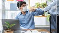 Two business colleagues greet each other by bumping elbows when meeting in office while wearing face mask Royalty Free Stock Photo