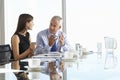 Two Business Colleagues Sitting Around Boardroom Table Having Informal Discussion