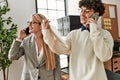 Two business executives smiling happy talking on the smartphone at the office Royalty Free Stock Photo