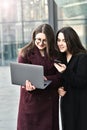 Two business girls working on a laptop on the background of the office, on the street Royalty Free Stock Photo