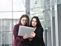 Two business girls working on a laptop on the background of the office, on the street Royalty Free Stock Photo