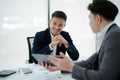 Two business men meeting to talking or discuss marketing work in workplace using paperwork, calculator, computer to work Royalty Free Stock Photo