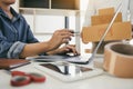 Two business owner are working together to pack products and check customers` orders on their laptops at home