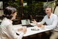 Two business partners discussing project details and using laptop during meeting in cafe Royalty Free Stock Photo