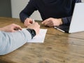 Two business people have meeting round a wooden table at an office. One writing one listening