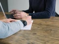 Two business people have meeting round a wooden table at an office. One writing one typing on laptop