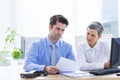 Two business people looking at a paper while working on computer Royalty Free Stock Photo