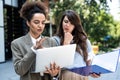 Two business people, working women, smiling and looking at each other one holding laptop other plans and documents with statistics Royalty Free Stock Photo