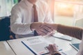 Two business shaking hands to each other above signed contract