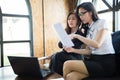 Two business woman sit on sofa and see document on hand, they talk about business plan and marketing share