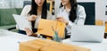 Two business women collaborate in a modern office, working on e-commerce packaging and startup ideas with laptops, teamwork Royalty Free Stock Photo